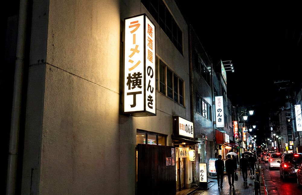 ビルの壁面から突き出して光る内照式袖看板